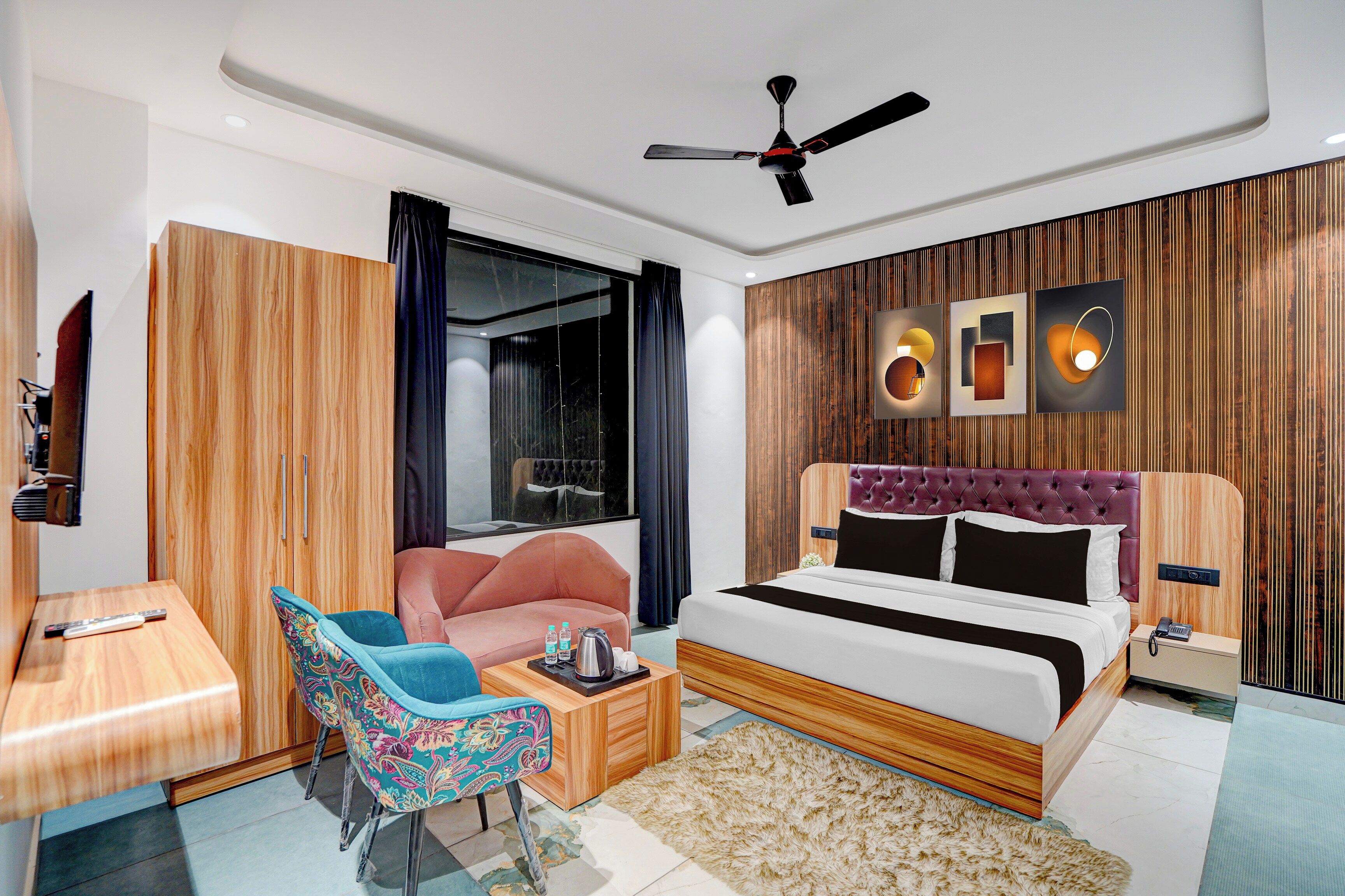 Habitación de hotel moderna con cama, zona de estar, televisor y ventilador de techo.