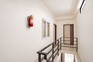 Un pasillo con extintor montado en la pared, una ventana y una puerta con un letrero de número.