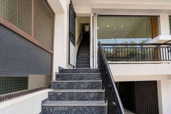 A staircase with a metal railing leading to a landing with a glass door.