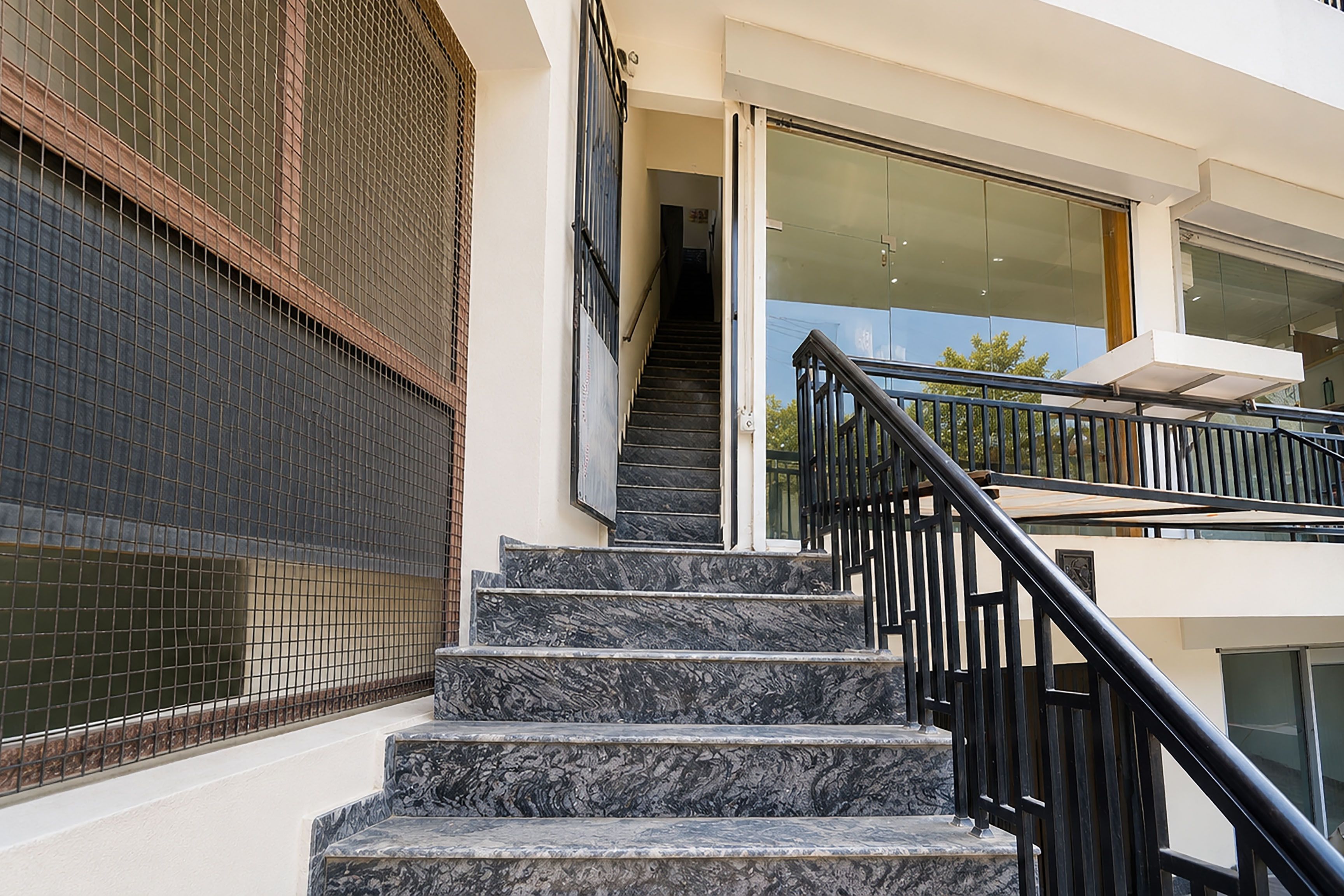 Eine Treppe mit schwarzen Geländern führt zu einem Balkon im zweiten Stock.