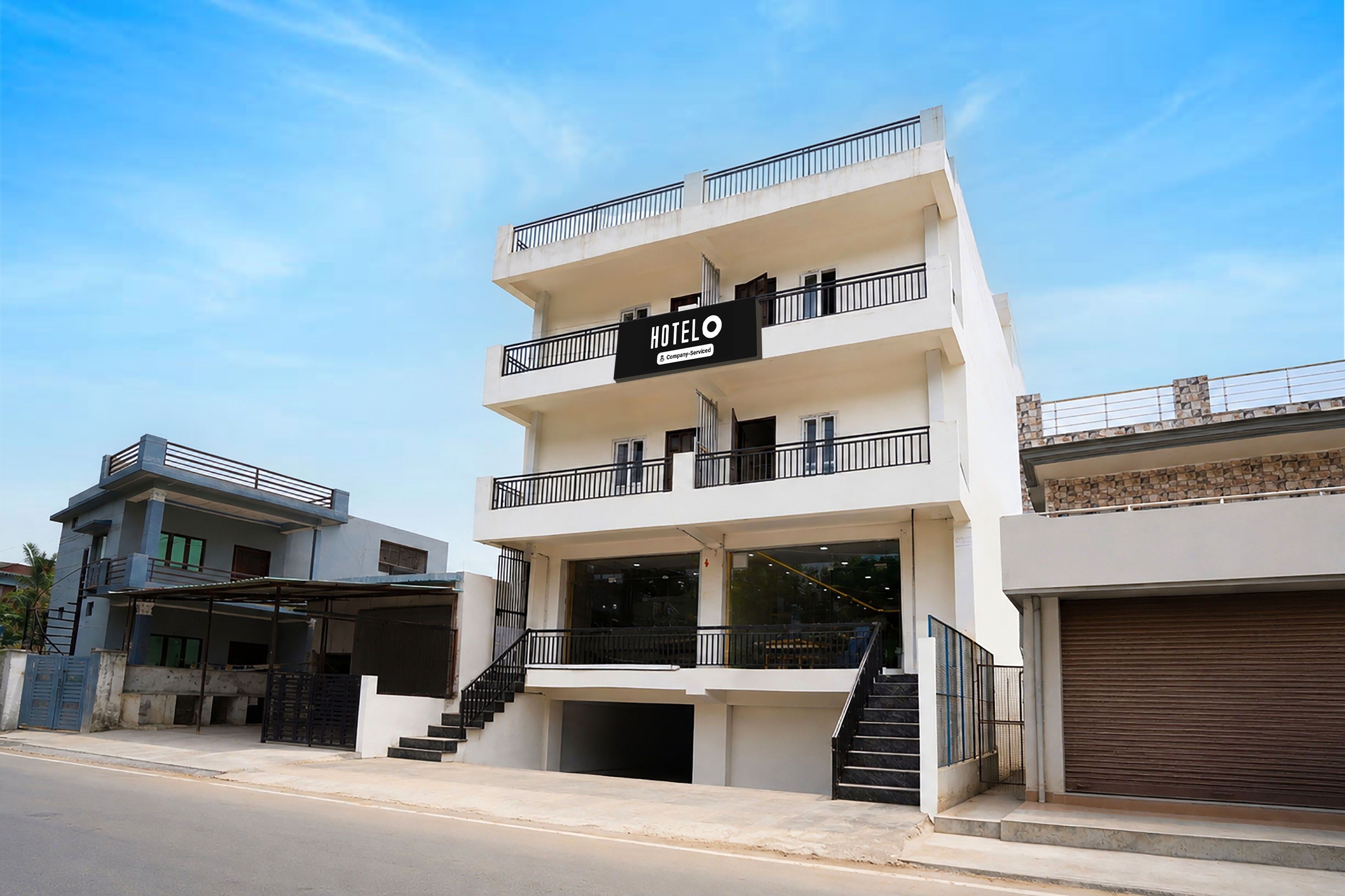 Un hotel de varios pisos con un letrero que indica que ofrece servicios corporativos. Cada piso tiene balcones, y una escalera conduce a la entrada.