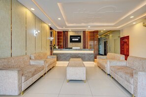 A hotel reception area with a marble reception desk, two sofas, a coffee table, and a Buddha statue. - Townhouse Oak Phase 13 Varanasi (Varanasi)