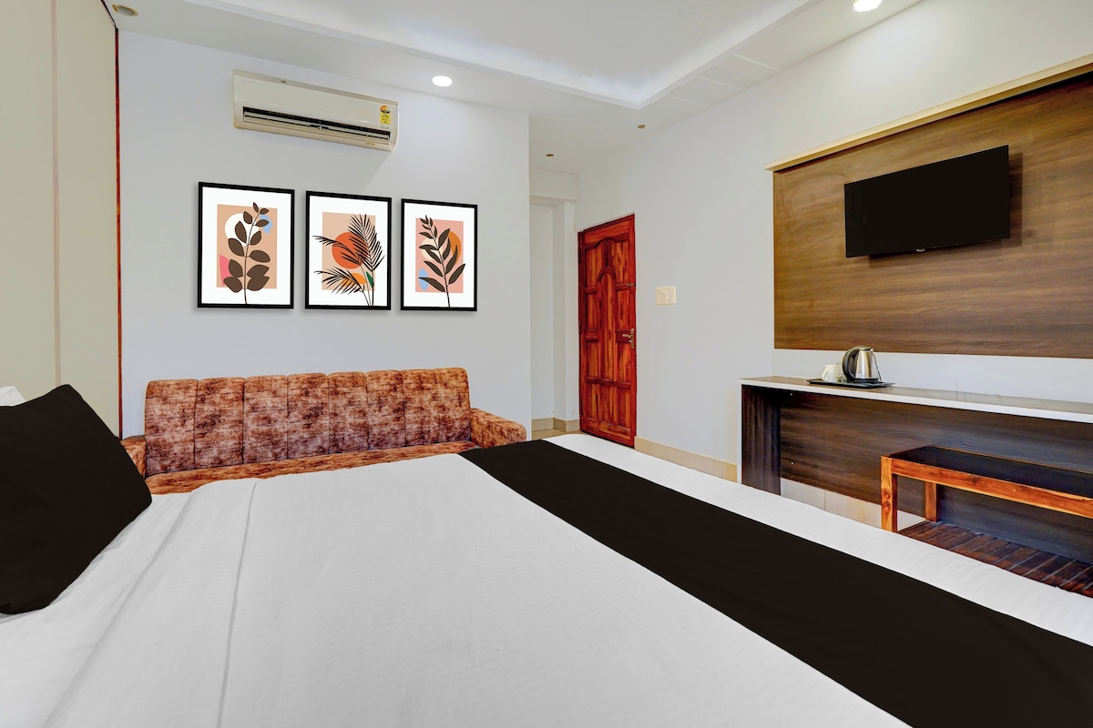 Una habitación de hotel con una cama, un sofá, un televisor montado en la pared y un armario de madera.