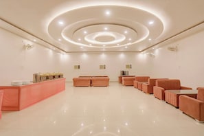 Un vestíbulo amplio con una zona de estar central, una mesa de recepción y un diseño de techo moderno.