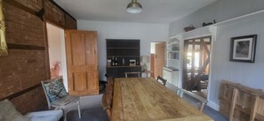 A dining area with a wooden table and chairs, a blackboard, and a bookshelf. - Comfortable country retreat in a rural village. Pet and family friendly! (White Colne)