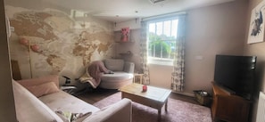 A living room with a couch, a chair, a coffee table, a television, and a map on the wall. - Comfortable country retreat in a rural village. Pet and family friendly! (White Colne)