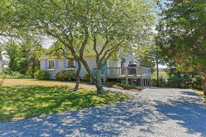 A two-story house with a covered porch and a gravel driveway. - Cape Cod Escape: Sweeping Views & Outer Cape Adventures RPAM130 (Eastham)