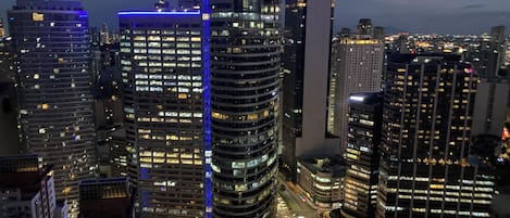 Une vue nocturne d’une ville, avec des gratte-ciel illuminés et une rue animée.