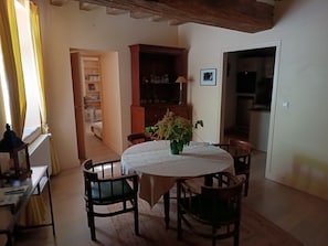 Un coin repas avec une table ronde, des chaises, un vase de fleurs et une bibliothèque.