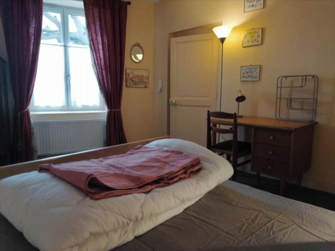 Une chambre à coucher avec un lit, un bureau, une chaise et une lampe.