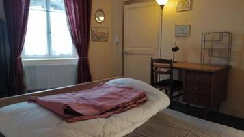 Une chambre à coucher avec un lit, un bureau, une chaise et une lampe.