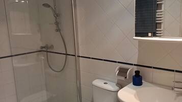 Une salle de bain moderne avec une douche à parois de verre, des toilettes et un lavabo avec un miroir au-dessus.