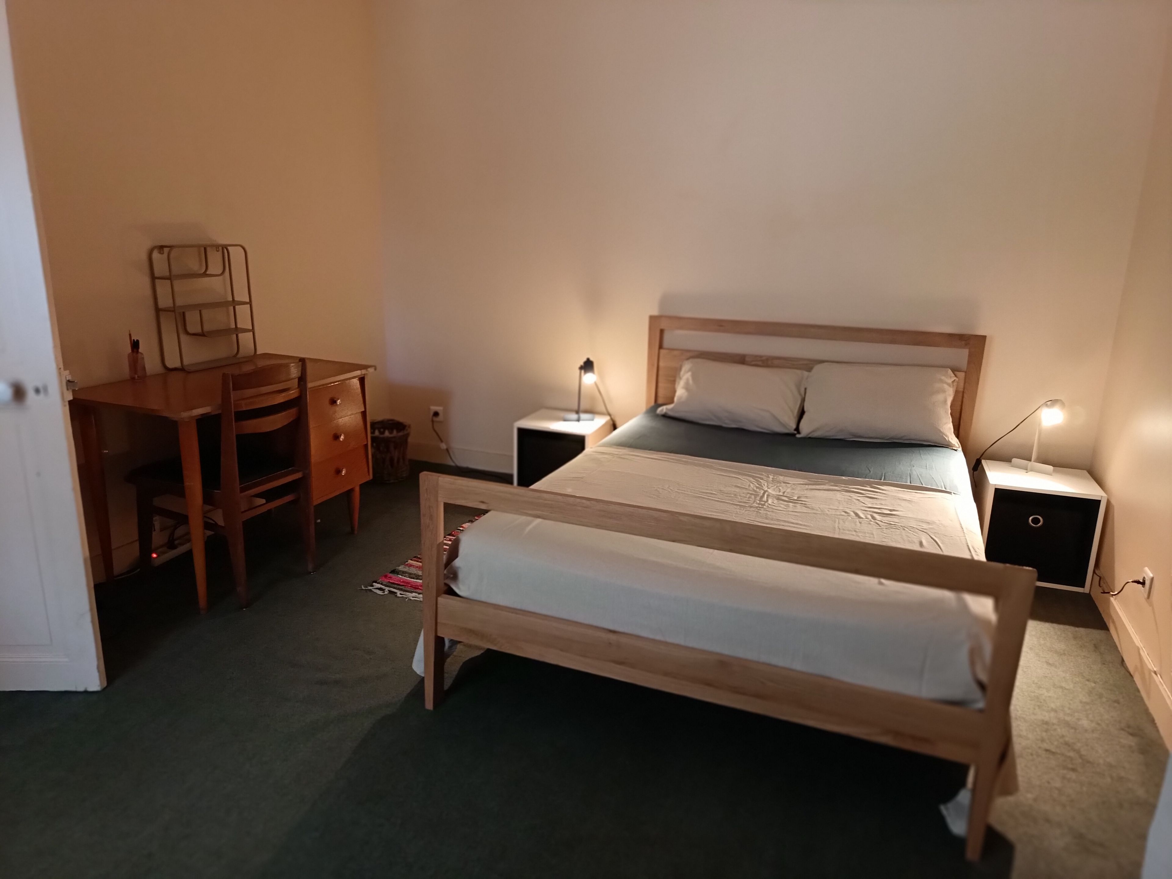 Une chambre avec un lit double, un bureau, deux tables de chevet et une chaise.
