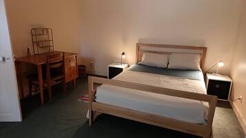 Une chambre avec un lit double, un bureau, deux tables de chevet et une chaise.