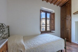 A bedroom with a bed, a window, a wardrobe, and a radiator. - A cozy and elegant 60-square-meter apartment spread over two floors, ideal for three guests (please note: no elevator; there are internal and external steps). This independent townhouse, located within a courtyard, is situated in the San Concordio distri (Lucca)