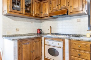 Cozinha com armários de madeira, forno embutido e bancada de granito.