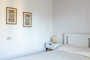 A minimalist bedroom with a bed, a nightstand, and two framed pictures on the wall. - A cozy and elegant 60-square-meter apartment spread over two floors, ideal for three guests (please note: no elevator; there are internal and external steps). This independent townhouse, located within a courtyard, is situated in the San Concordio distri (Lucca)