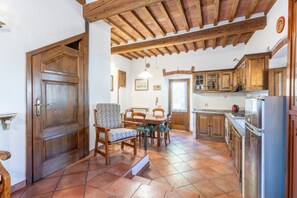 A kitchen with wooden cabinets, a dining table with chairs, and a tiled floor. - A cozy and elegant 60-square-meter apartment spread over two floors, ideal for three guests (please note: no elevator; there are internal and external steps). This independent townhouse, located within a courtyard, is situated in the San Concordio distri (Lucca)