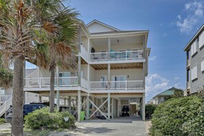 A multi-story beachfront building with balconies, a covered entrance, and a parking area. - The Bella Vista Beachfront Retreat + Pool, Elevator, Golf Cart & Ice Maker (Surf City)