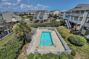A residential area with a swimming pool surrounded by a wooden deck and a white fence. - The Bella Vista Beachfront Retreat + Pool, Elevator, Golf Cart & Ice Maker (Surf City)