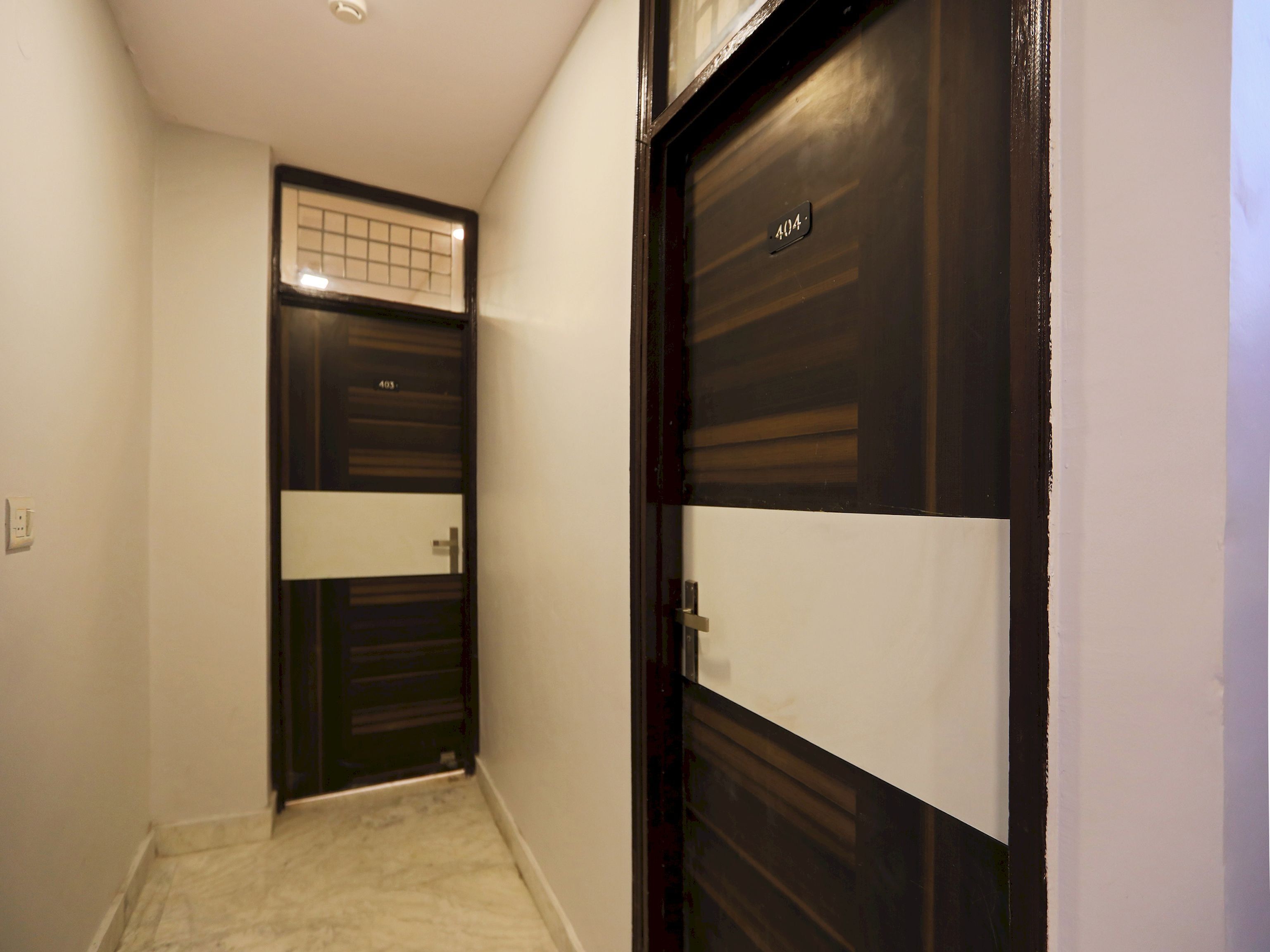 Un pasillo con una puerta de madera oscura numerada 404, una pared de color claro y un suelo de baldosas.
