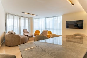 A modern living room with a large marble coffee table, comfortable seating, and large windows with sheer curtains. - Sodeco Ashrafieh by Stayinn (Beirut)