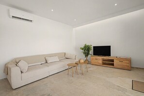 A minimalist living room with a sofa, a coffee table, a TV stand, and a potted plant. - Holiday Home 'Lo Tamariu' with Private Pool, Wi-Fi and Air Conditioning (Deltebre)