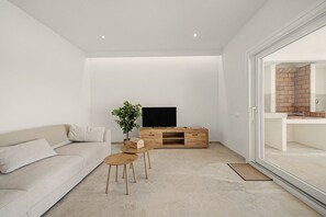 A modern living room with a sofa, coffee table, TV stand, and a potted plant. - Holiday Home 'Lo Tamariu' with Private Pool, Wi-Fi and Air Conditioning (Deltebre)