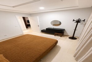 A bedroom with a bed, a bedside table, a mirror, and a coat stand. - Cozy & Bright Aouina Apartment (Site archéologique de Carthage)