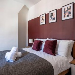 A hotel room with a bed, pillows, a blanket, and wall art. - Gateshead - Stay5 - Free Parking - Transport Links (Gateshead)