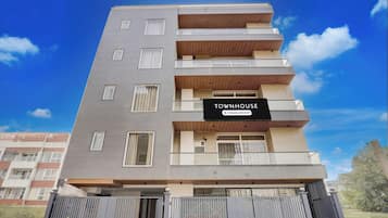A multi-story residential building with a sign indicating it is a company-serviced townhouse.