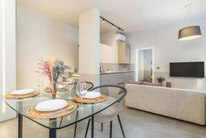 Un comedor moderno con una mesa de vidrio, sillas y un florero con flores.