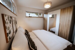 A bedroom with a bed, a window, and a mirror.