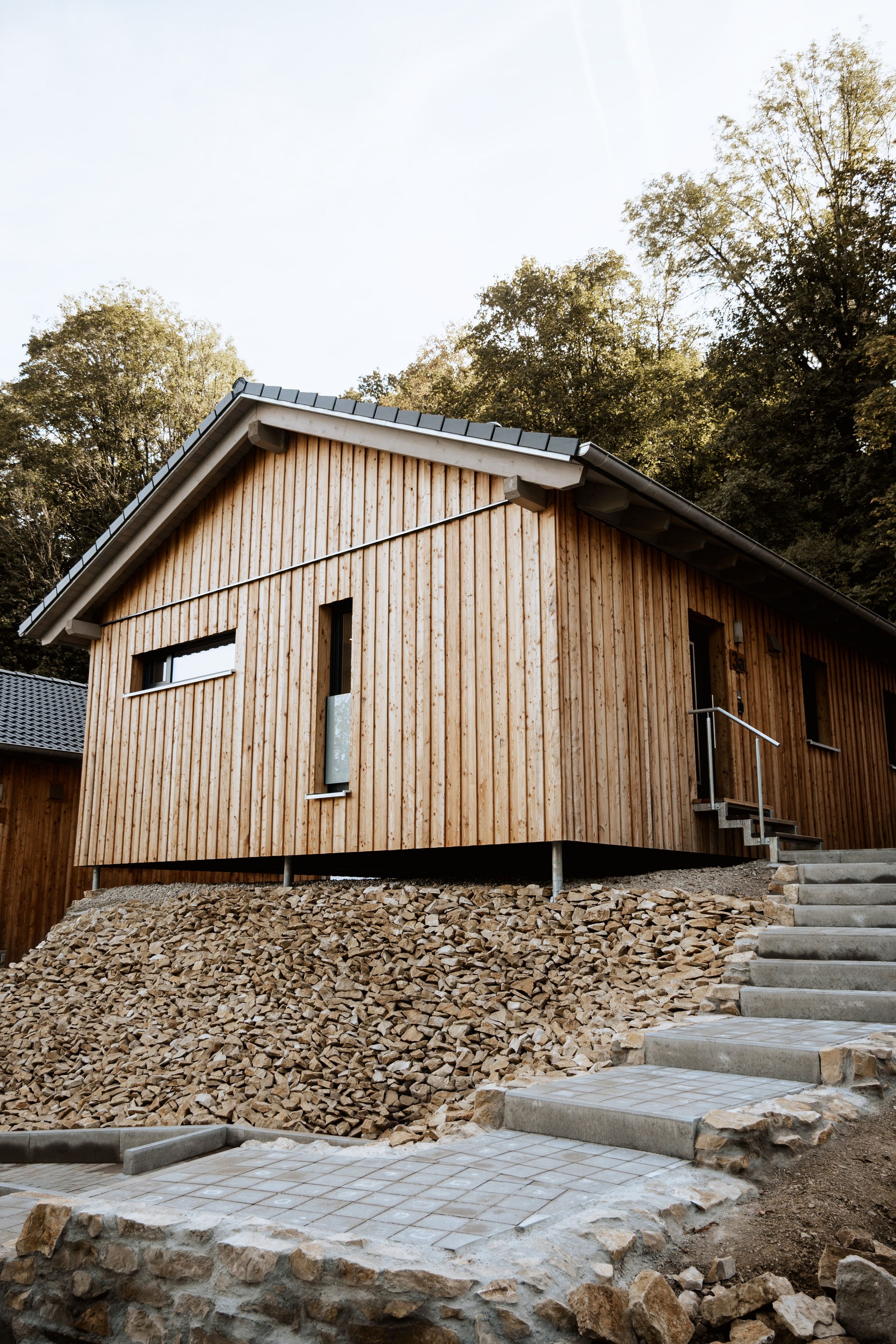 A wooden building with a sloped roof, a small window, and a staircase leading up to the entrance.