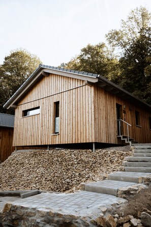 A wooden building with a sloped roof, a small window, and a staircase leading up to the entrance.