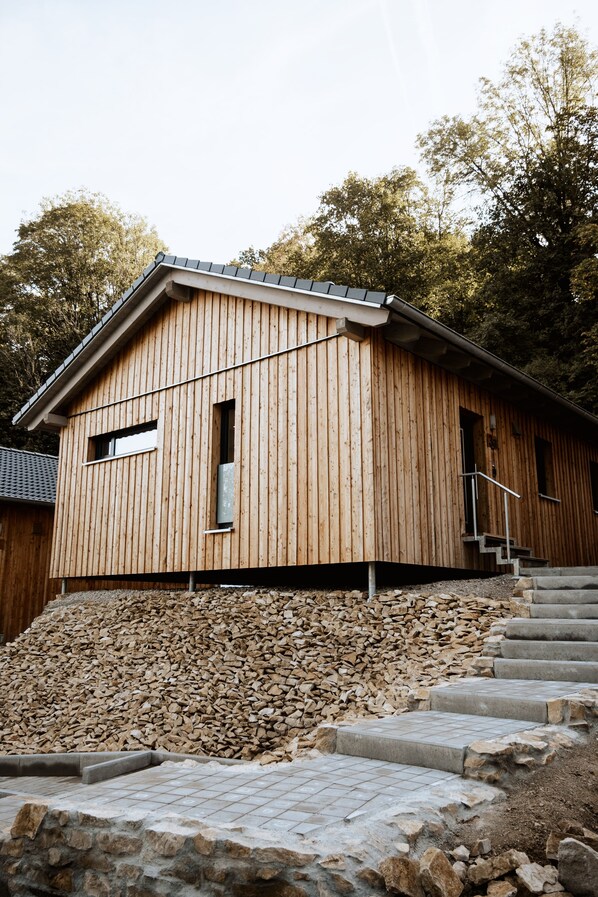 A wooden building with a sloped roof, a small window, and a staircase leading up to the entrance.