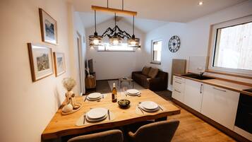 Eine moderne Küche mit einem Holzespeisetisch, gedeckt für vier Personen, einem eingebauten Backofen und einem Fenster mit Blick.