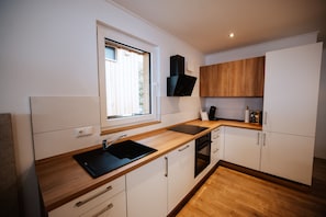 A modern kitchen with a wooden countertop, a black sink, and white cabinetry.