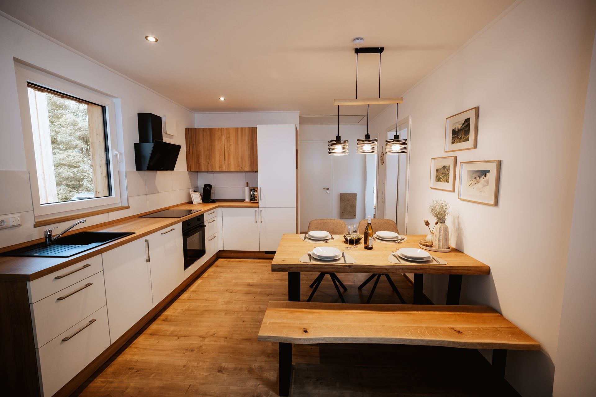 Een moderne keuken met een houten aanrecht, witte kastjes en een eethoek met een houten tafel en een bank.