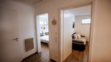 A hallway with a bed, a sofa, and a door leading to another room.