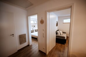 A hallway with a bed, a sofa, and a door leading to another room. - Holiday Home 'JURA-ALM' with Mountain View, Private Terrace and Wi-Fi (Pommelsbrunn)