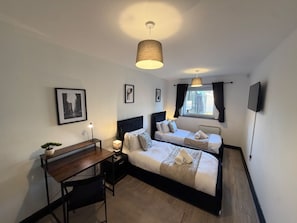 A hotel room with two beds, a desk, a lamp, and a television. - Oak & Noir 2 Bed 2 Bath Wifi Free Parking Near Uni (Manchester)