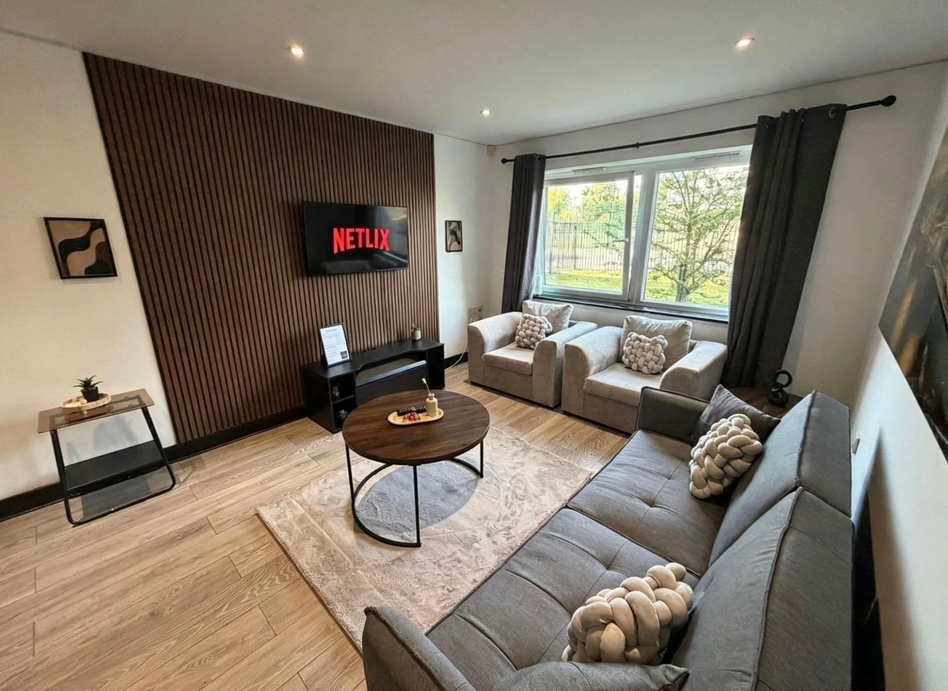 A modern living room with a sofa set, a coffee table, and a flat-screen TV mounted on the wall.