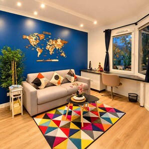 Ein modernes Wohnzimmer mit einer Weltkarte an der Wand, einer Couch, einem Couchtisch und Blick ins Freie durch ein Fenster.
