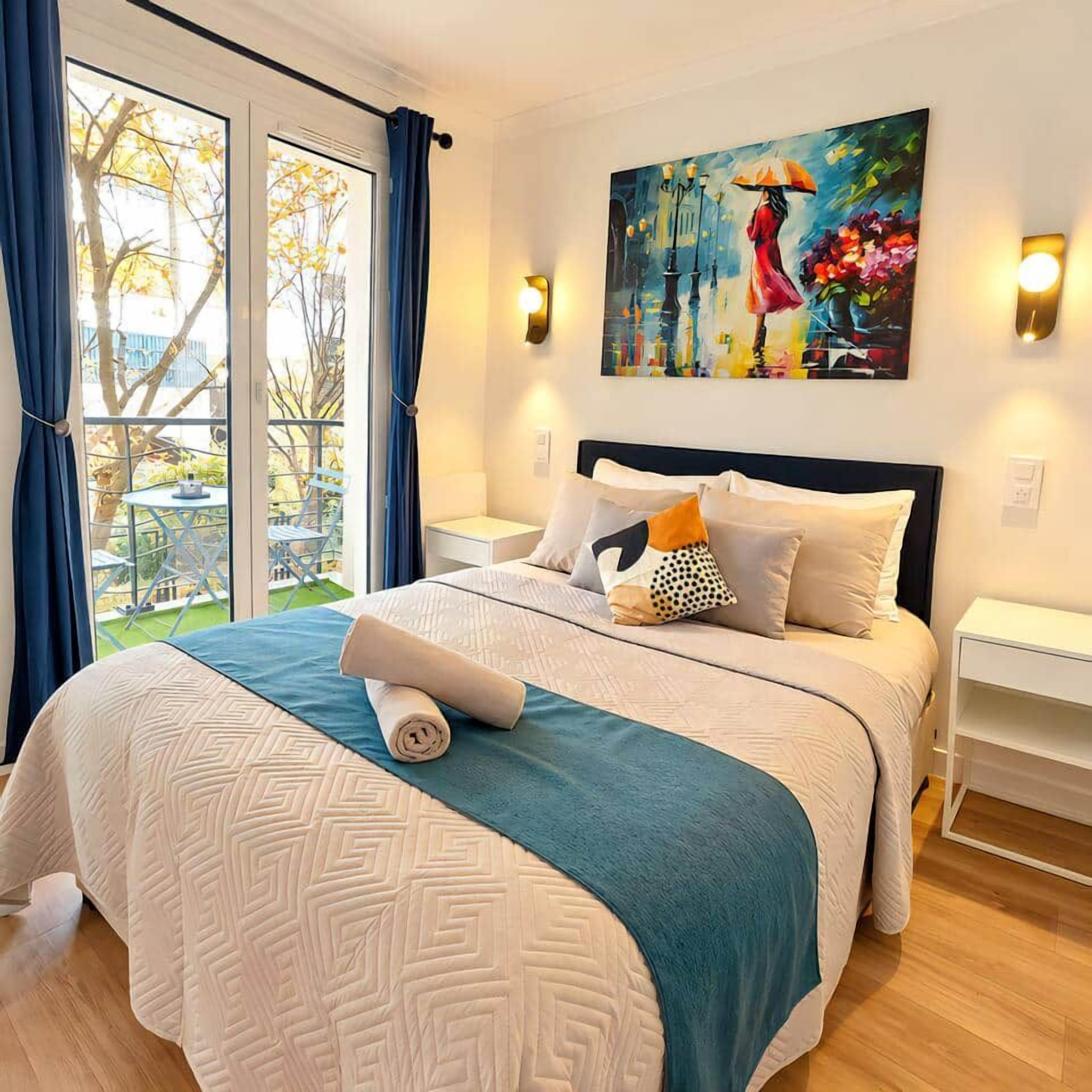 A hotel room with a large bed, a painting on the wall, and a view of the outdoors.