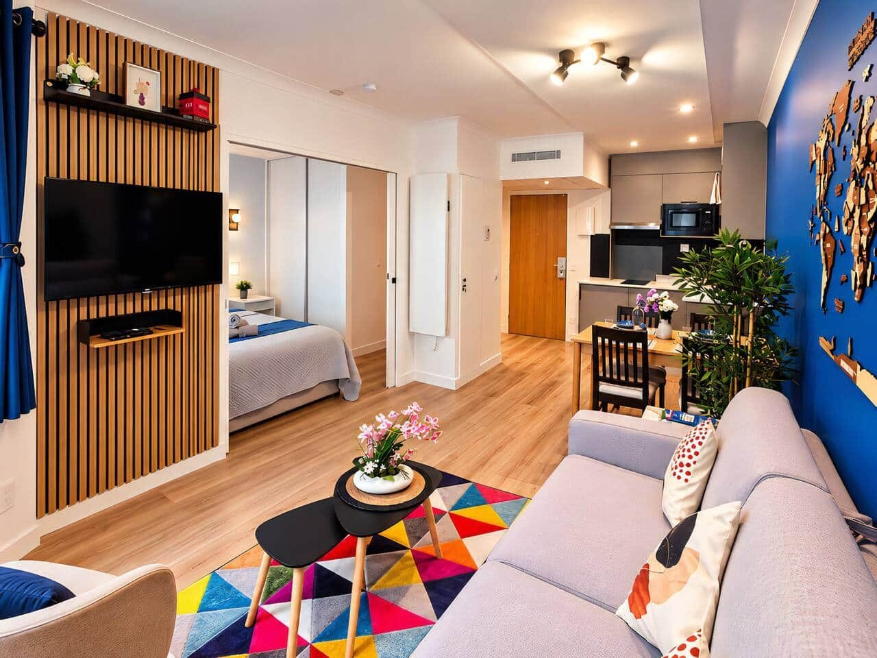 Una sala de estar moderna con un sofá, una televisión y un comedor con mesa y sillas.