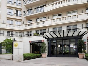 A multi-story building with a modern entrance featuring a glass door and a covered waiting area. - Paris Expo 5 min – Cozy 1BR Apt with Balcony (Issy-les-Moulineaux)