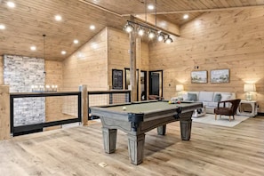 A wooden interior with a pool table, a sofa, and a stone wall. - Heated Pool • Theater Room • Creekside Setting (Sevierville)