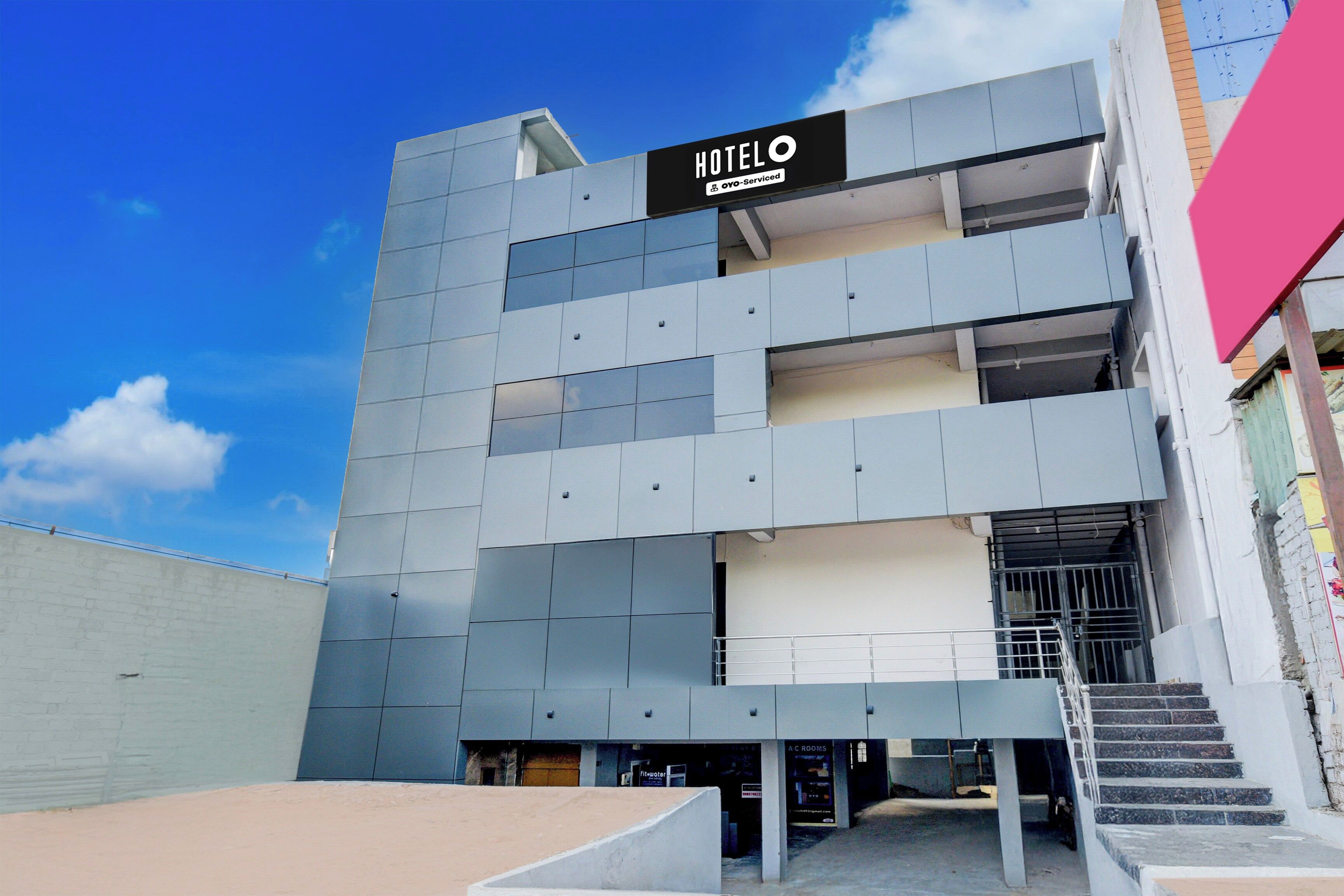A modern hotel building with a sign reading 'HOTELO' and 'OYO-Serviced'.