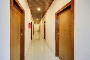 Un pasillo con puertas de madera, un extintor y un techo con diseño de cuadrícula.